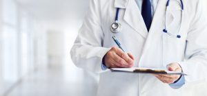 Male Doctor writing on clipboard