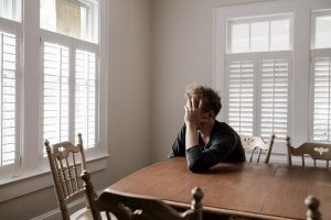 Stress and Recovery from Addiction. Stressed out man sitting at a kitchen table 
